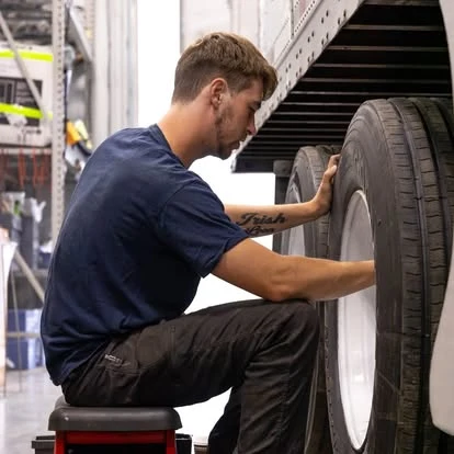 A Newport technician working beside a trailer wheel